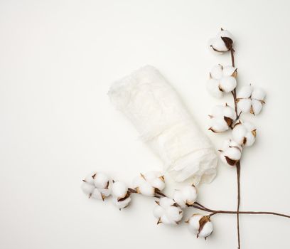 piece of white gauze and a sprig with white cotton flowers on the table