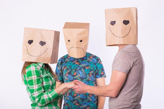 Love triangle, jealousy and unrequited love concept - woman and man with bags over heads holding hands and another man is angry.