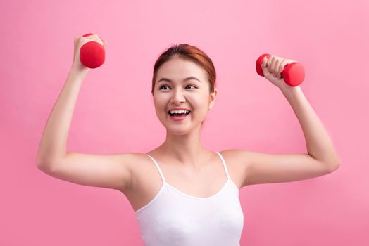 Woman Lifting Weights. Fitness woman lifting weights smiling happy on pink background.