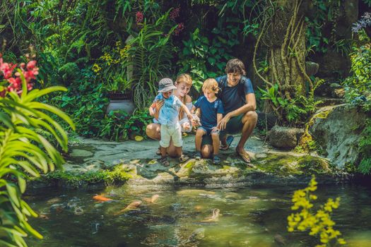 happy family feeding colorful Catfish in tropical pond