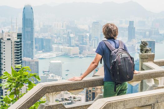 Young man traveler at the peak of Victoria against the backdrop of Hong Kong