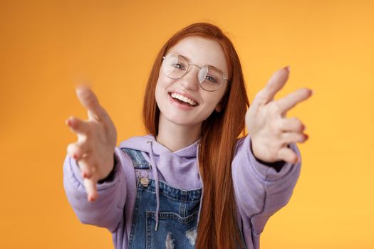 Come here let hold. Attractive silly friendly happy smiling redhead woman stretch arms camera grab product wanna tight friendship hugs grinning embracing cuddling besties, orange background