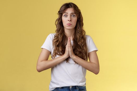 Pretty please beg you help me. Innocent cute lovely upset caucasian girl begging pleading your mercy pulling face hope for pity apologizing puppy eyes frowning need urgent advice yellow background