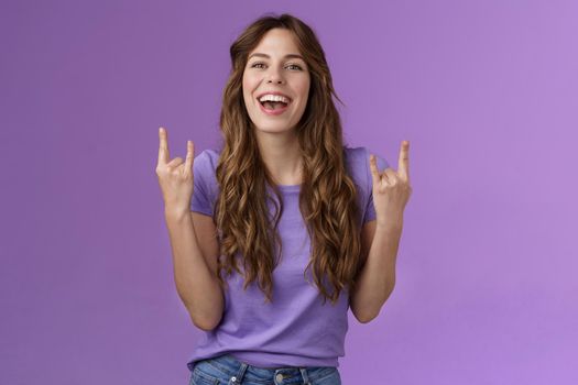 This summer holidays rock. Happy enthusiastic cheerful girl having fun enjoy awesome party weekends smiling broadly say yeah joyful make heavy-metal sign stand purple background amused