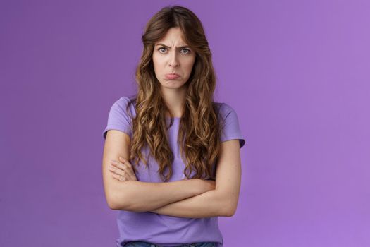 Offended silly timid cute girl sulking pouting lips frowning whining upset cross hands block pose insulted look moody camera disagree acting childish complaining unfair game purple background