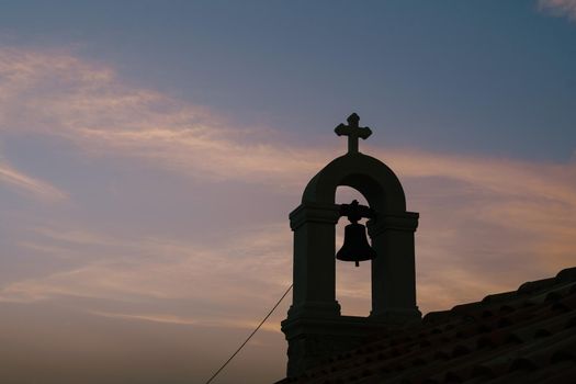 Bell on the bell tower against the background of the sunset sky