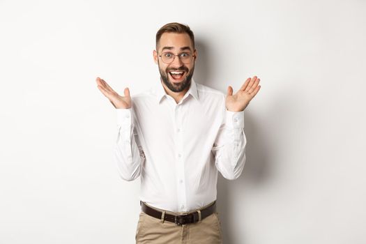 Surprised happy male entrepreneur clap hands and smiling, looking amazed at camera, standing over white background