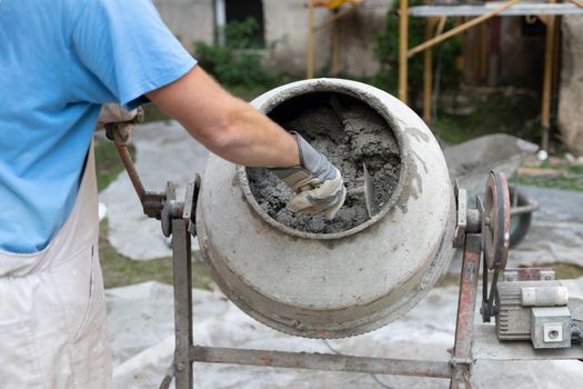 Labore worker operating concrete cement mixer at construction site.