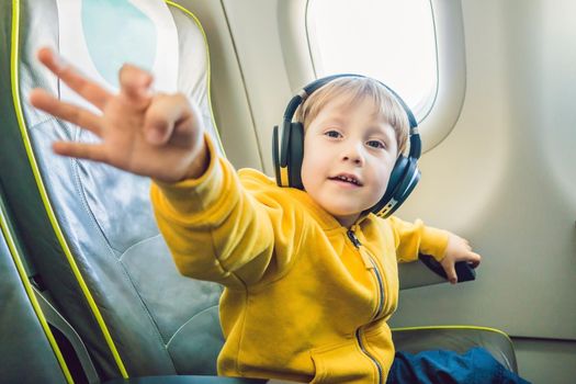 Boy with headphones watching and listening to in flight entertainment on board airplane