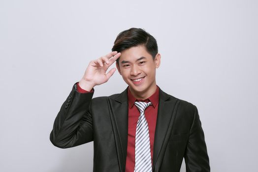 Smart casual man wearing black suit, pointing fingers to forehead standing on white background in studio