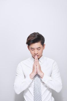 Young handsome business man praying with hands together asking for forgiveness smiling confident.
