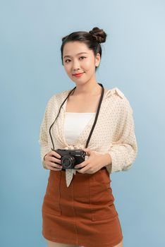 Attractive energetic Asian girl happily holding cemara isolated on blue studio background