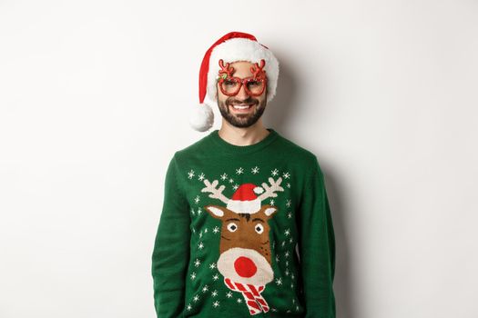 Christmas holidays, celebration concept. Happy man in Santa hat and funny party glasses standing against white background.