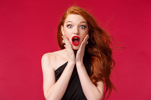 Makeup, beauty and women concept. Close-up portrait of shocked and surprised redhead woman found out surprising news, hold hands on cheeks look with compassion and amazement camera