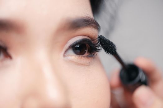 Close up beside applying mascara brush on eyelash.