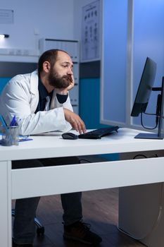 Specialist falling asleep while working on computer at desk
