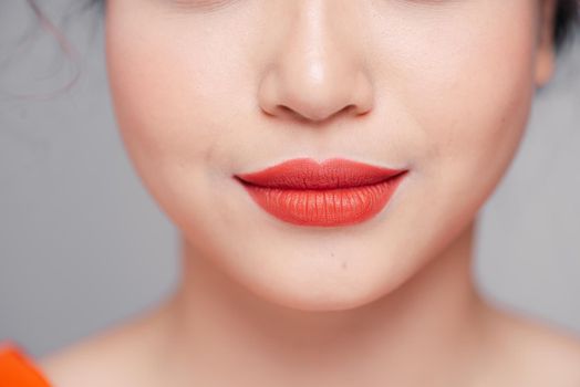 Close up view of beautiful woman lips with coral matt lipstick