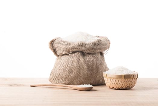 White rice in burlap sack and bowl on top of wooden table