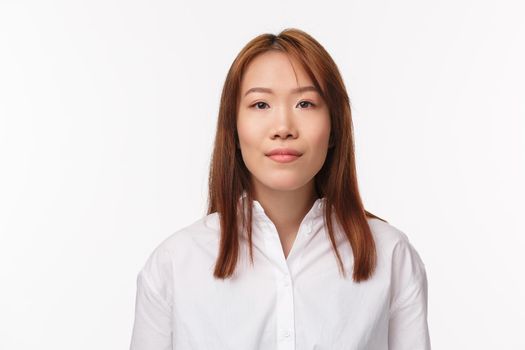 Close-up portrait of elegant young office lady, businesswoman in formal white collar shirt, smiling at camera pleasant, look determined and professional, standing white background