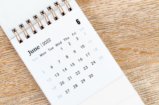 June 2022 desk calendar on wooden background.