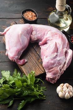 Fresh raw rabbit with olive oil, rosemary, peppers , on old dark wooden table background