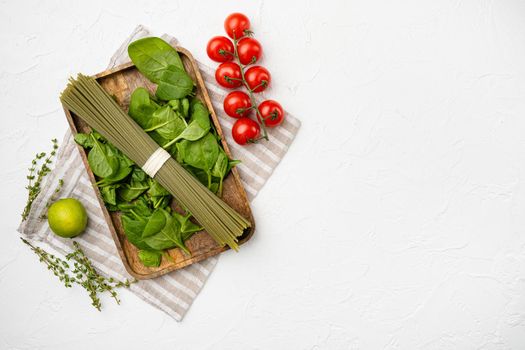Green colored spaghetti raw dry spinach, on white stone table background, top view flat lay, with copy space for text