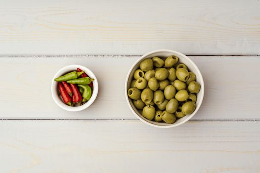 Olives in a bowl on wooden background, top view