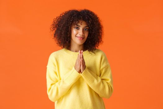 Girl feeling relish is near, something good will happen. Pleased and assertive, confident african-american woman clasp hands and smiling, awaiting, anticipating luck, orange background