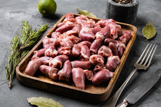 Raw poultry hearts offal with herbs, on gray stone table background