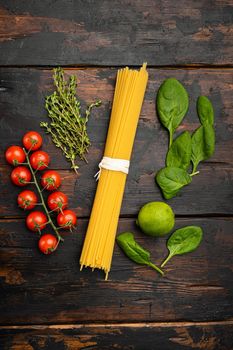 Bunch of spaghetti, raw pasta, on old dark wooden table background, top view flat lay