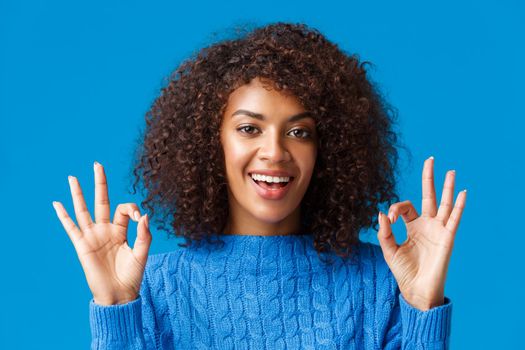 Close-up shot assured and assertive, confident young african american woman say everything under control, alright all good with okay gesture, smiling give approval, positive reply, blue background