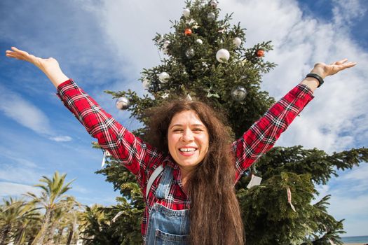 Christmas and holiday concept - Happy jumping woman over Christmas tree background