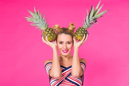 Fashion portrait woman with sunglasses and pineapple over pink background.