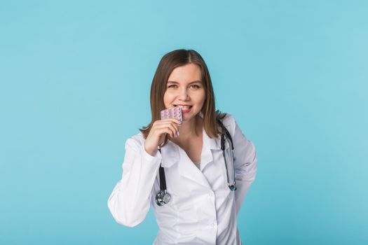 Young female doctor tasting pack of pills