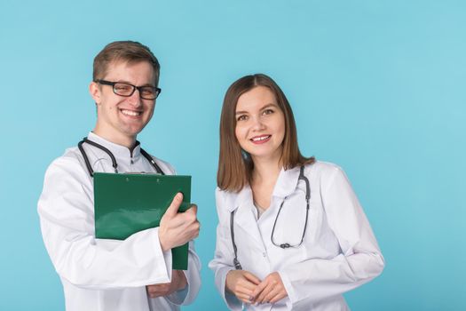 Two best smart professional smiling doctors workers in white coats smiling standing against blue background