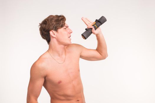 Expression, fitness and gesture concept - Handsome sporty man singing with dumbbell over white background