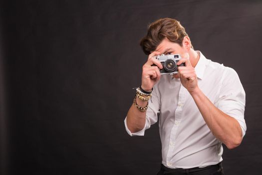 People, photographer and vintage concept - man searching for an interesting subject for his photo holding a vintage camera on brown background with copy space