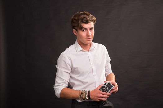 People, photographer and vintage concept - man searching for an interesting subject for his photo holding a vintage camera on brown background