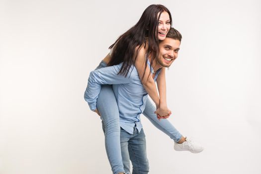 Young male carrying his girlfriend piggyback. They are fooling around
