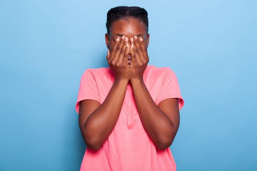Portrait of terrified introvert african american young woman covering face with her hands