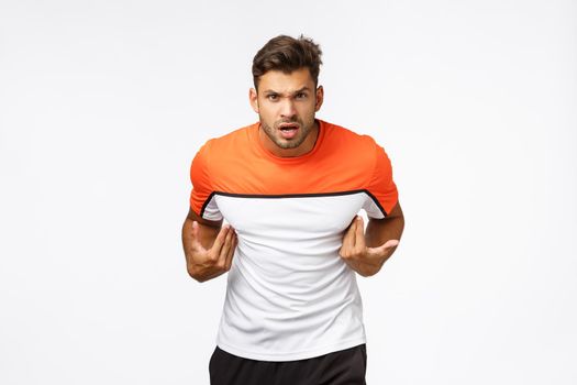 Offended aggressive young sportsman look frustrated and angry, was accused something ridiculous, pointing himself and stare camera puzzled. Masculine strong man insulted, arguing, white background