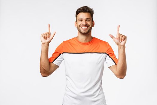 Waist-up cheerful, good-looking bearded man in good shape, enjoy workout, dedicate life to sport and fitness, raising hands, pointing up, smiling suggest and recommend try product, white background