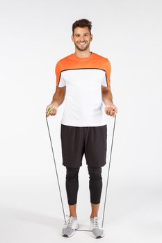 Health key to happiness. Full-length happy charming sportsman in activewear, jumping using jump rope and smiling camera, workout, train endurance, motivated lose weight, white background