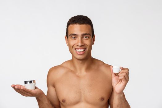 Photo of shirtless african american man smiling and holding cream isolated over white background