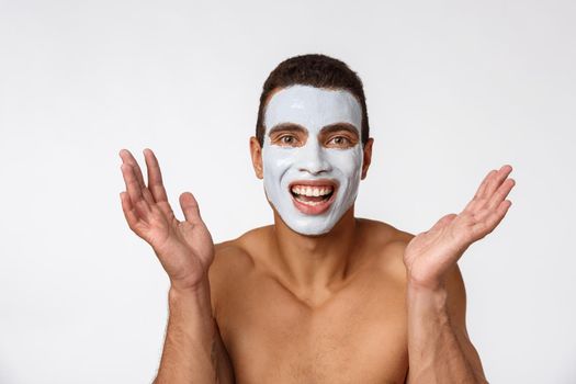 Photo of shirtless african american man smiling and applying face cream isolated over white background
