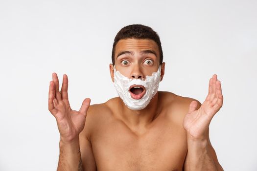 Close up of a happy naked african man with face in shaving foam isolated over gray background