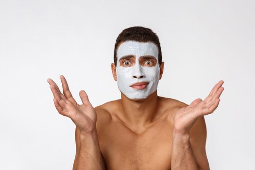 Photo of shirtless african american man smiling and applying face cream isolated over white background