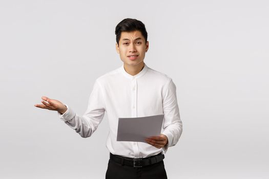 Skeptical and displeased asian male entrepreneur complaining unsatisfied with received documents, shrugging extend hand sideways in dismay, frowning upset, talking to employees