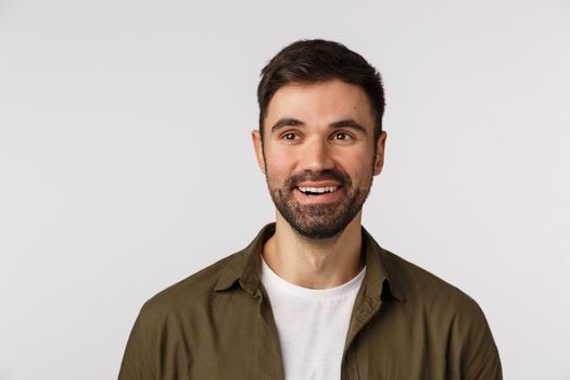 Guy check out interesting event, looking pleased with satisfied smile. Attractive bearded man in coat over t-shirt, looking left and smirking delighted, watching impressive performance