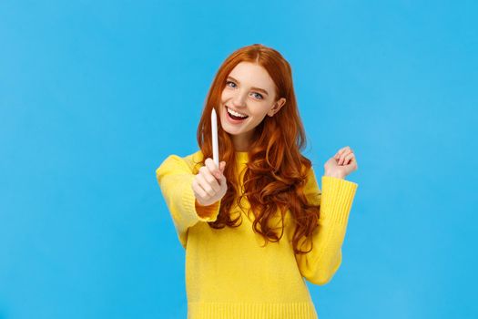 Be author of your own future. Cheerful and creative excited redhead woman giving you pen and smiling, want autograph, want friend draw something, smiling joyfully, standing blue background